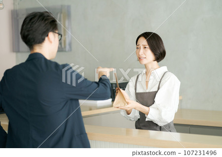 A female clerk handing over a paper bag A female clerk handing over a paper bag 107231496