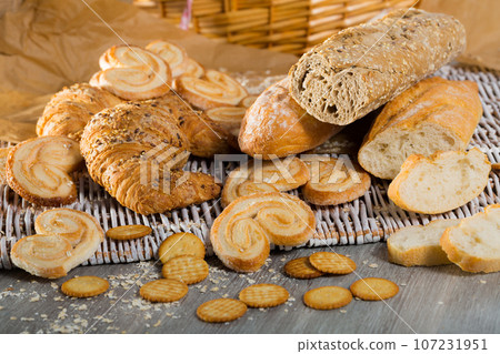 Wheat and grain baguettes, croissants and biscuits on wicker mat Wheat and grain baguettes, croissants and biscuits on wicker mat 107231951