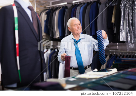 Mature senior citizen chooses fashionable tie in clothing store 107232104