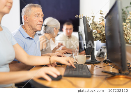 Concentrated elderly man immersed in using computer in library 107232120