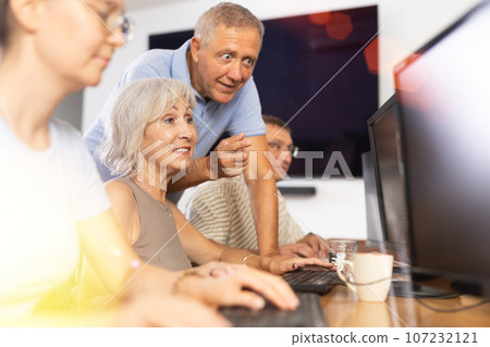Old woman learning computer programs with teacher in training room Old woman learning computer programs with teacher in training room 107232121