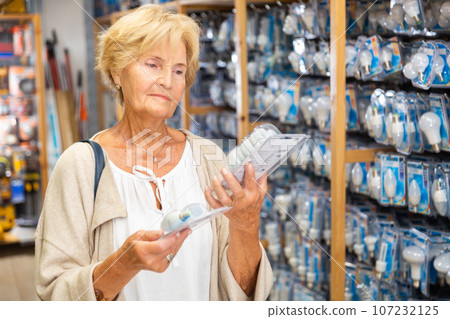 Mature woman choosing light bulb at store 107232125