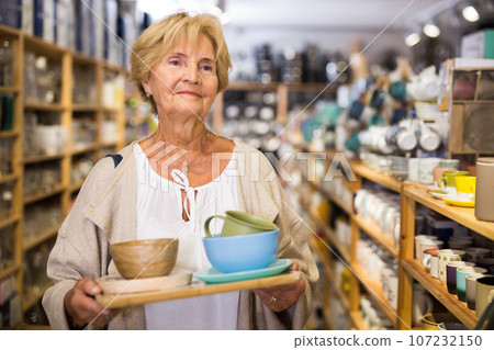 Mature woman choosing new dishes at store 107232150