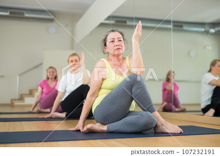 Woman making yoga meditation in half king of fish yoga pose - ardha matsyendrasana Woman making yoga meditation in half king of fish yoga pose - ardha matsyendrasana 107232191