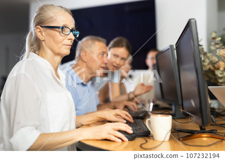 Old woman learning computer programs in training room 107232194