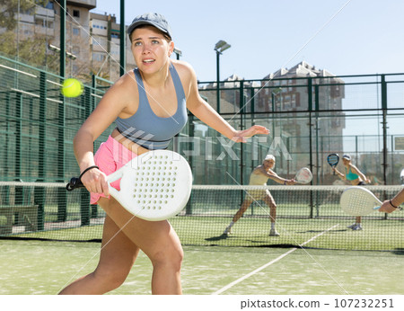 Determined sporty young woman doing her best playing padel in court 107232251