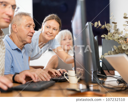 Senior man attending computer class under guidance of young female teacher Senior man attending computer class under guidance of young female teacher 107232510