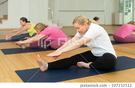 Women making yoga at gym. Paschimottanasana pose Women making yoga at gym. Paschimottanasana pose 107232512