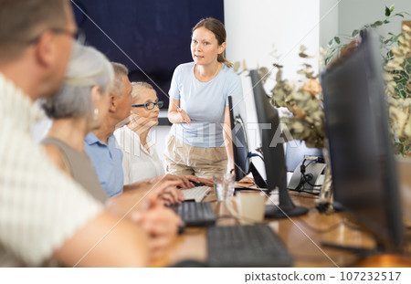 Woman teacher teaching elderly people how to use computer Woman teacher teaching elderly people how to use computer 107232517