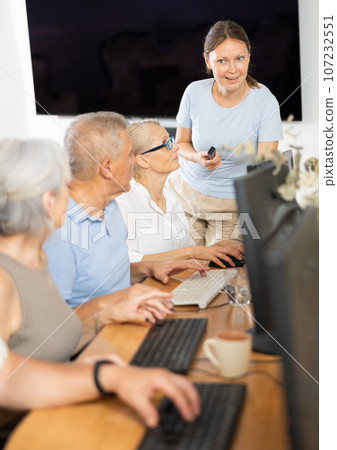 Woman teacher teaching elderly people how to use computer 107232551