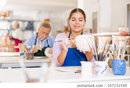 Woman learning to paint pottery at pottery class Woman learning to paint pottery at pottery class 107232589