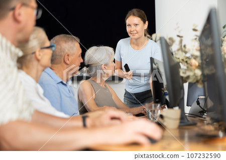 Middle-aged woman teacher speaking to mature attendees of computer courses Middle-aged woman teacher speaking to mature attendees of computer courses 107232590