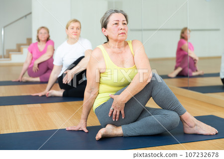 People practicing stretching yoga training in class - marichiasana pose People practicing stretching yoga training in class - marichiasana pose 107232678