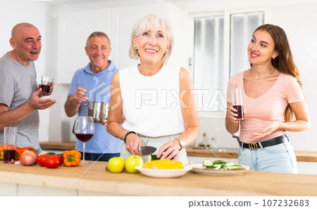 Happy family with elderly parents preparing lunch in modern kitchen Happy family with elderly parents preparing lunch in modern kitchen 107232683
