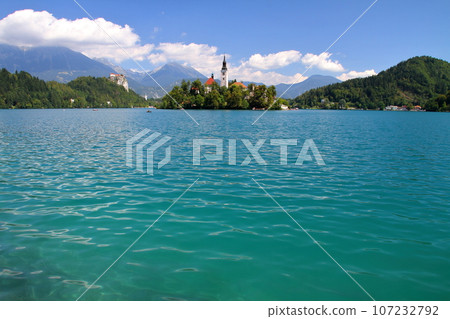 Lake Bled in Slovenia, Southern Europe - Church of the Assumption of the Virgin Mary on Bled Island, Bled Castle and the Julian Alps floating on the surface of the lake 107232792