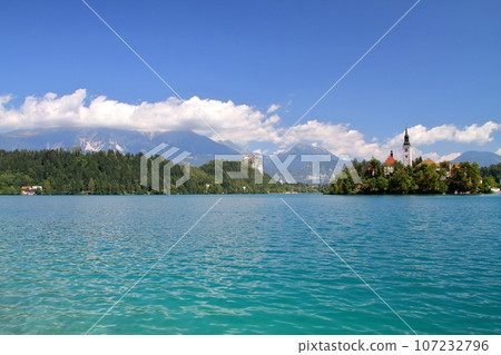 Lake Bled in Slovenia, Southern Europe - Church of the Assumption of the Virgin Mary on Bled Island, Bled Castle and the Julian Alps floating on the surface of the lake 107232796
