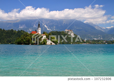 Lake Bled in Slovenia, Southern Europe - Church of the Assumption of the Virgin Mary on Bled Island, Bled Castle and the Julian Alps floating on the surface of the lake 107232806
