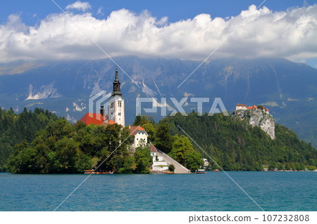 Lake Bled in Slovenia, Southern Europe - Church of the Assumption of the Virgin Mary on Bled Island, Bled Castle and the Julian Alps floating on the surface of the lake 107232808
