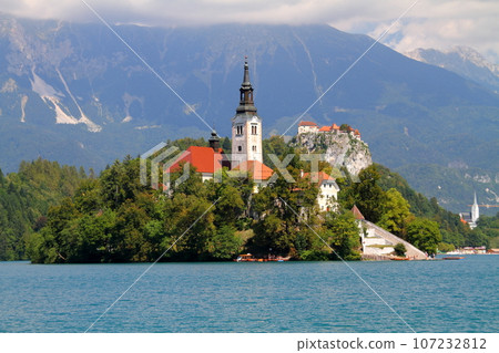 Lake Bled in Slovenia, Southern Europe - Church of the Assumption of the Virgin Mary on Bled Island, Bled Castle and the Julian Alps floating on the surface of the lake Lake Bled in Slovenia, Southern Europe - Church of the Assumption of the Virgin Mary on Bled Island, Bled Castle and the Julian Alps floating on the surface of the lake 107232812