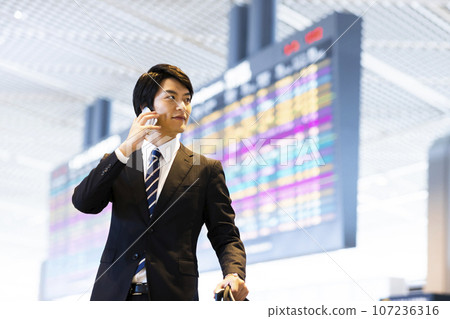 Young businessman on a business trip from the airport calling on his smartphone 107236316