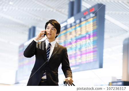 從機場出差的年輕商人打電話給他的智慧型手機 107236317