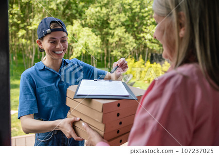 Courier delivering parcel, customer signs the delivery documents. Courier delivering parcel, customer signs the delivery documents. 107237025