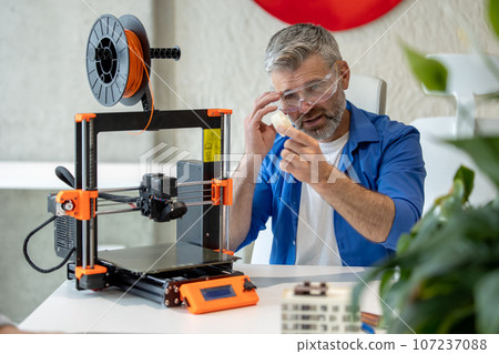 Technician printing in 3d printer, using three dimensional printing machine for work. Technician printing in 3d printer, using three dimensional printing machine for work. 107237088