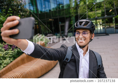 Smiling businessman in hemlet on a scooter making selfie Smiling businessman in hemlet on a scooter making selfie 107237138