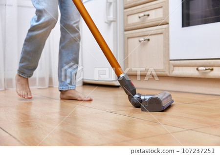 woman uses cordless vacuum cleaner to clean floor. woman uses cordless vacuum cleaner to clean floor. 107237251
