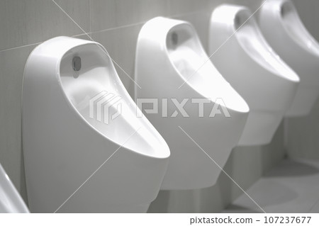Close up row of indoor urinals men. toilet room interior background on modern tower. Close up row of indoor urinals men. toilet room interior background on modern tower. 107237677