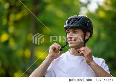 Young handsome cyclist putting on his protective hemlet 107237764