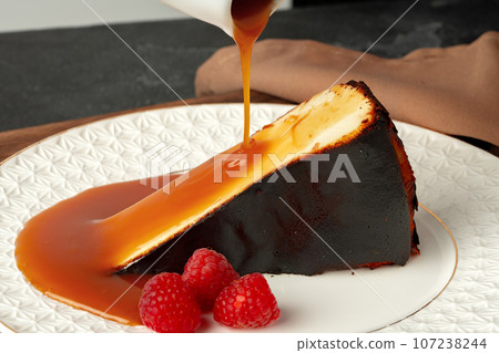 Piece of cheesecake with pouring caramel sauce on plate Piece of cheesecake with pouring caramel sauce on plate 107238244