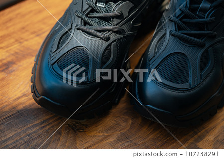 Close up of black sport shoes on wooden background Close up of black sport shoes on wooden background 107238291