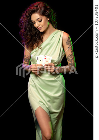 Attractive young female poker player holding pair of winning aces Attractive young female poker player holding pair of winning aces 107238401