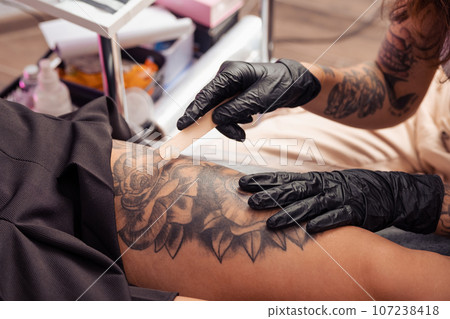 Experienced tattoo master applying healing cream on tattooed skin Experienced tattoo master applying healing cream on tattooed skin 107238418