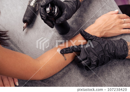 Tattoo artist applying soothing sanitising foam on tattooed skin Tattoo artist applying soothing sanitising foam on tattooed skin 107238420