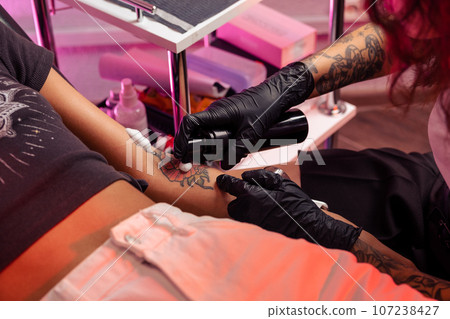 Professional tattoo artist applying antibacterial foam on tattooed skin 107238427