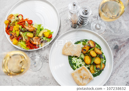 Fried squid with spinach sauce, baked potatoes and asparagus on a white plate Fried squid with spinach sauce, baked potatoes and asparagus on a white plate 107238632