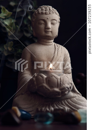 stone statue of buddha with a candle 107239255