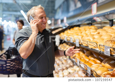 Man takes muffins on shelf of bakery section Man takes muffins on shelf of bakery section 107239547