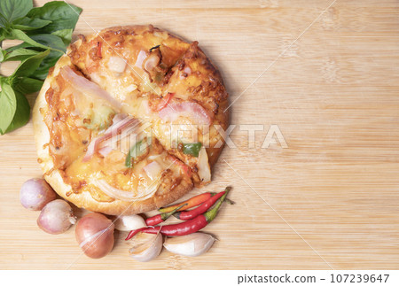 Pizza on wooden board with fresh peppers and basil with garlic on copy space background Pizza on wooden board with fresh peppers and basil with garlic on copy space background 107239647