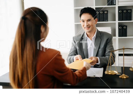 justice and law concept.passing bribe money in the envelop at lawyer office. businessman hand taking bribe money from female. justice and law concept.passing bribe money in the envelop at lawyer office. businessman hand taking bribe money from female. 107240439