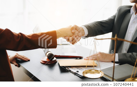 Man lawyer hand and women client shaking hand collaborate on working agreements with contract documents at the modern office. Man lawyer hand and women client shaking hand collaborate on working agreements with contract documents at the modern office. 107240441