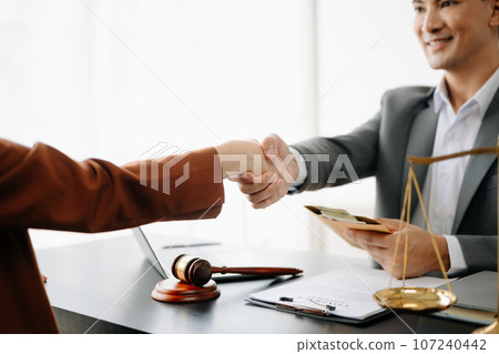 Man lawyer hand and women client shaking hand collaborate on working agreements with contract documents at the modern office. Man lawyer hand and women client shaking hand collaborate on working agreements with contract documents at the modern office. 107240442