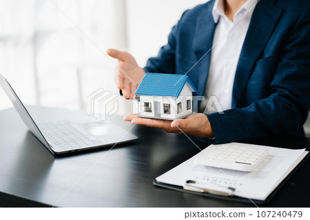 Buying a home or insurance deal, an insurance agent pointing a pen to those interested in renting a house, a contract, signing an Home buying agreement in office. 107240479