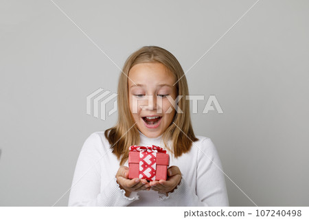 Portrait of happy excited child with surprise gift present on white background Portrait of happy excited child with surprise gift present on white background 107240498