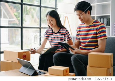 Starting small businesses SME owners, two check online orders Selling products working with boxs freelance work on sofa at home using tablet and laptop marketing, packaging, concept. Starting small businesses SME owners, two check online orders Selling products working with boxs freelance work on sofa at home using tablet and laptop marketing, packaging, concept. 107241304