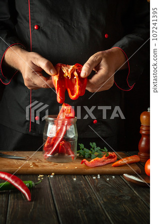 Chef preparing fresh vegetables in the kitchen. The cook puts fresh peppers in a jar in the kitchen. Healthy or vegetarian food concept Chef preparing fresh vegetables in the kitchen. The cook puts fresh peppers in a jar in the kitchen. Healthy or vegetarian food concept 107241395