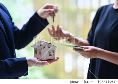 Close up view hand of property realtor giving house keys to new owner after signing contract. Real estate, mortgage and loan Close up view hand of property realtor giving house keys to new owner after signing contract. Real estate, mortgage and loan 107241963