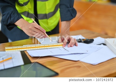 Cropped shot of architect reviewing blueprints working on sketch of a new construction project at office 107241972